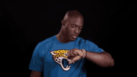 a man wearing a blue shirt with a jaguar on it is standing in front of a black background .
