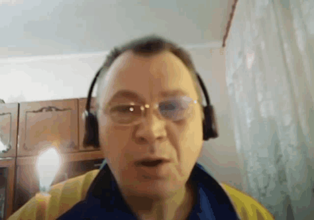 a man wearing headphones and glasses looks at the camera