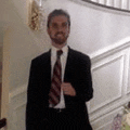 a man in a suit and tie is standing next to a staircase .