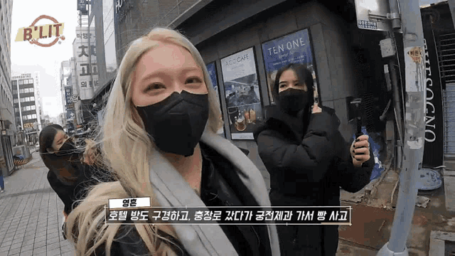 two women wearing face masks in front of a ten one sign
