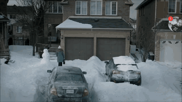 two cars are parked in front of a house with a snowman in the driveway