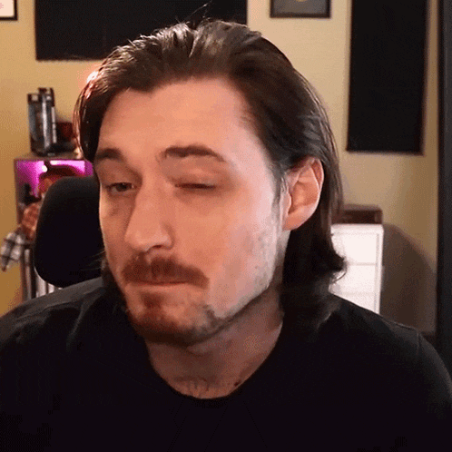 a man with long hair and a beard is looking at the camera