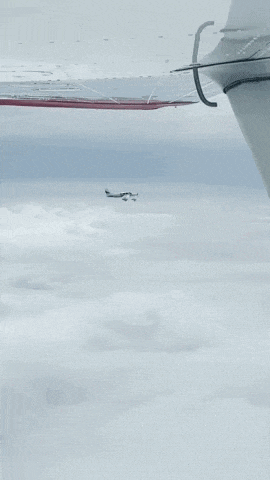 a plane is flying through the clouds with a red stripe on the tail