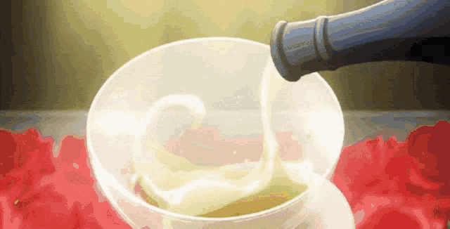 a bottle is being poured into a glass on a table