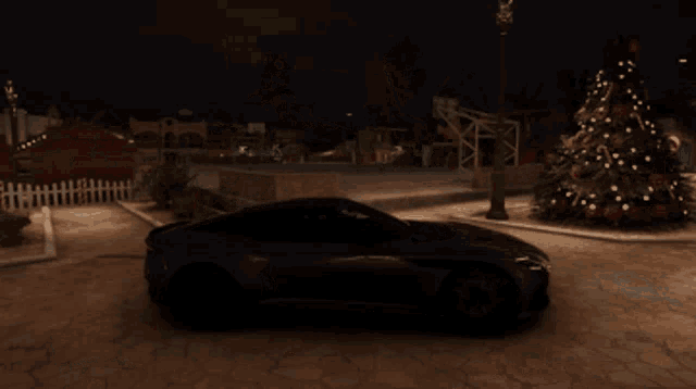 a green sports car is parked near a christmas tree