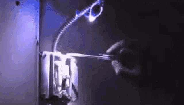 a person is holding a pair of scissors in front of a light switch .