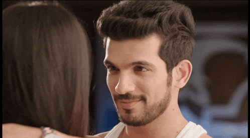 a man with a beard looks at a woman with dark hair