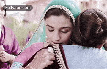 a woman is hugging another woman while holding a piece of paper .