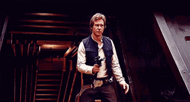 han solo from star wars is holding a gun in his hand and making a funny face .
