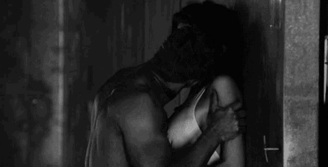 a black and white photo of a man and a woman kissing .