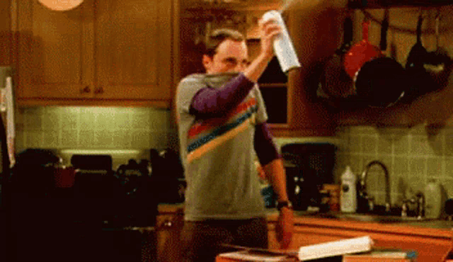 a man in a striped shirt is holding a napkin in a kitchen