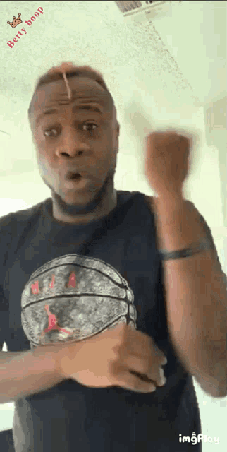 a man in a black shirt with a basketball on it is making a funny face