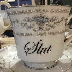a cup and saucer with the word slut written on it are on a table .