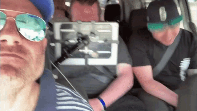 a man wearing sunglasses is sitting in a car with two other men