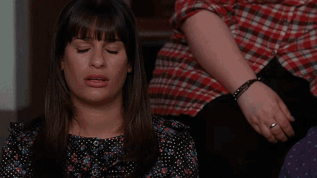 a woman laying down with her eyes closed and a plaid shirt on