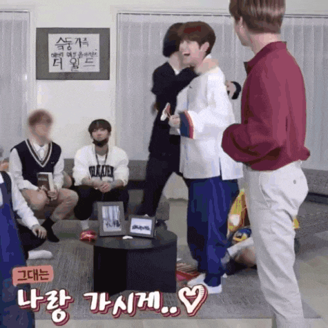 a group of young men are standing in a living room with a sign on the wall that says ' seoul ' on it