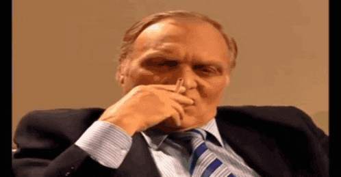 a man in a suit and tie is holding something in his nose