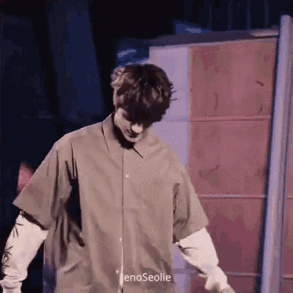 a man in a brown shirt is standing on a stage .
