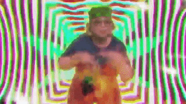 a man is standing in front of a rainbow colored background .