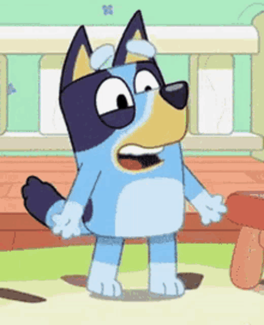a blue and yellow cartoon dog is standing next to a table and looking at the camera .