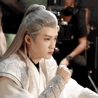 a man with long white hair is sitting in a chair