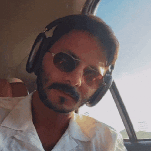 a man wearing sunglasses and headphones looks out the window