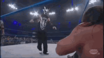 a wrestling match is taking place in a ring and a referee is watching .