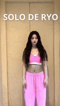 a woman in a pink crop top and pink sweatpants is standing in front of a door with the words solo de ryc on it
