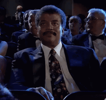 a man in a suit and tie is sitting in a theatre