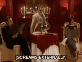 a group of people are sitting around a table and one of them is screaming