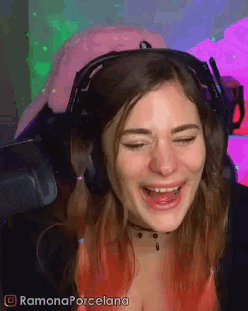 a woman wearing headphones and a pink hat is laughing .