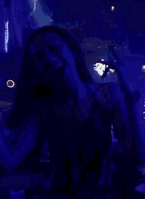 a woman is dancing in a dark room with a lot of blue lights .