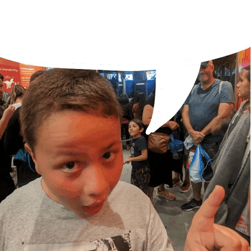 a boy wearing a grey shirt with a picture of a horse on it is giving a thumbs up sign