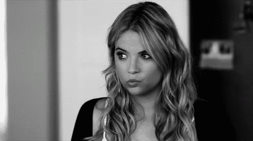 a black and white photo of a woman with long wavy hair making a funny face .
