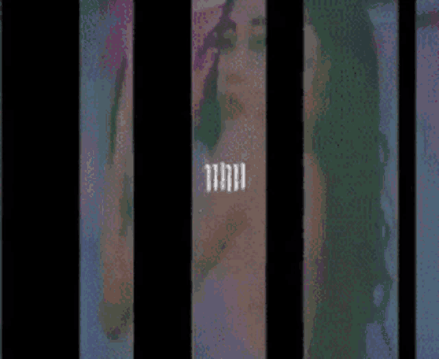 a woman with long hair is behind bars in a prison cell