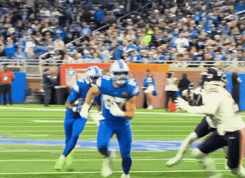 a football player in a blue uniform runs with the ball on the field