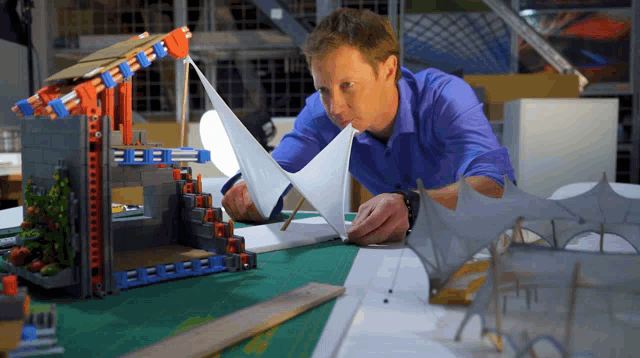 a man in a blue shirt is working on a model of a house