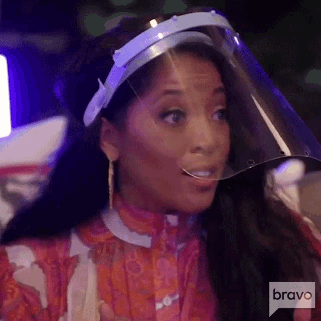 a woman is wearing a face shield and smiling while sitting at a table .