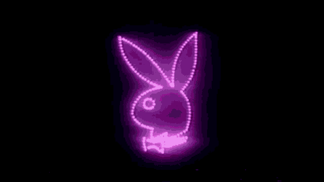 a purple playboy bunny logo is lit up in the dark .