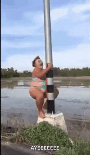 a woman in a bikini is hanging on a pole in the water .