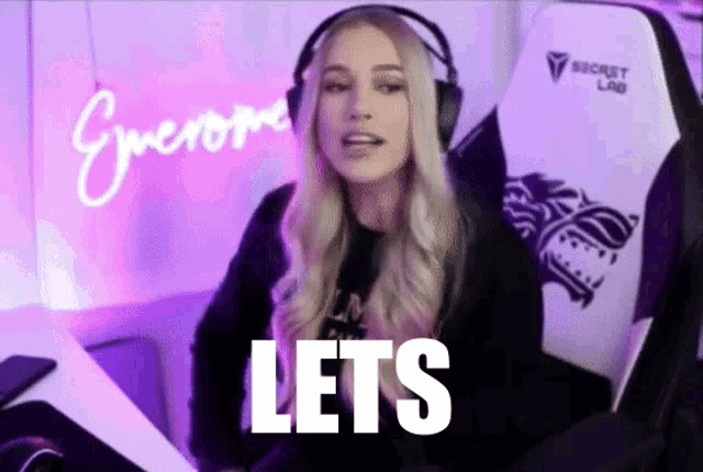 a woman wearing headphones is sitting in a gaming chair and saying lets
