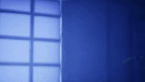 a window in a dark room with a blue light coming through it .