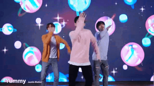 a group of young men are dancing in front of a screen that says yummy