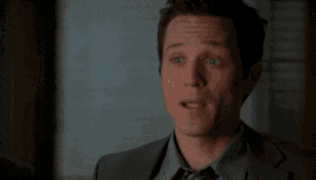 a man in a suit is standing in a dark room