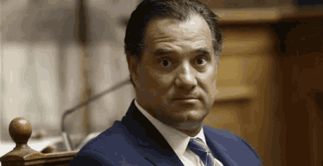 a man in a suit and tie looks at the camera with a serious look on his face