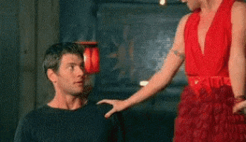 a woman in a red dress is touching the shoulder of a man in a black shirt .