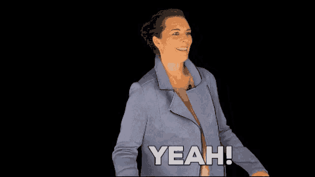 a woman in a blue jacket is smiling and saying yeah on a black background .