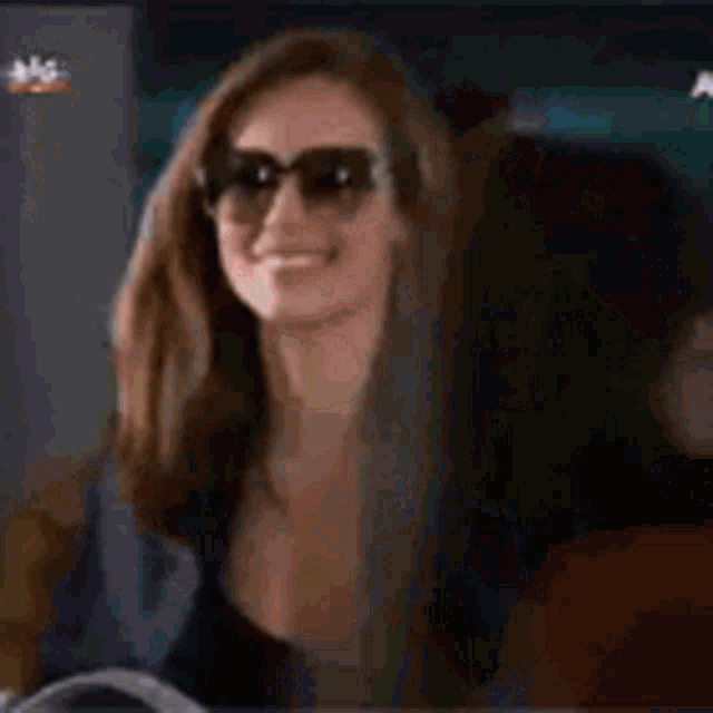 a woman wearing sunglasses and a black shirt is smiling .