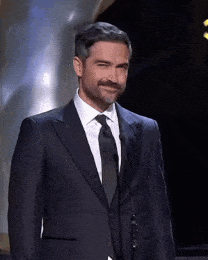 a man in a suit stands in front of a microphone