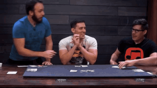 a group of men are playing a game of cards and one of them has a shirt that says music notes on it